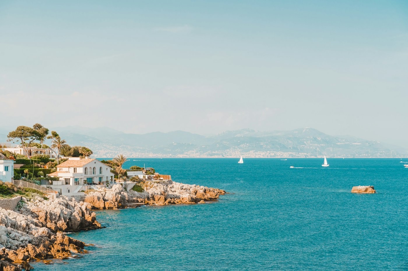 Une villa blanche posée sur la côte rocheuse de la presqu'île d'Antibes, face à la mer turquoise