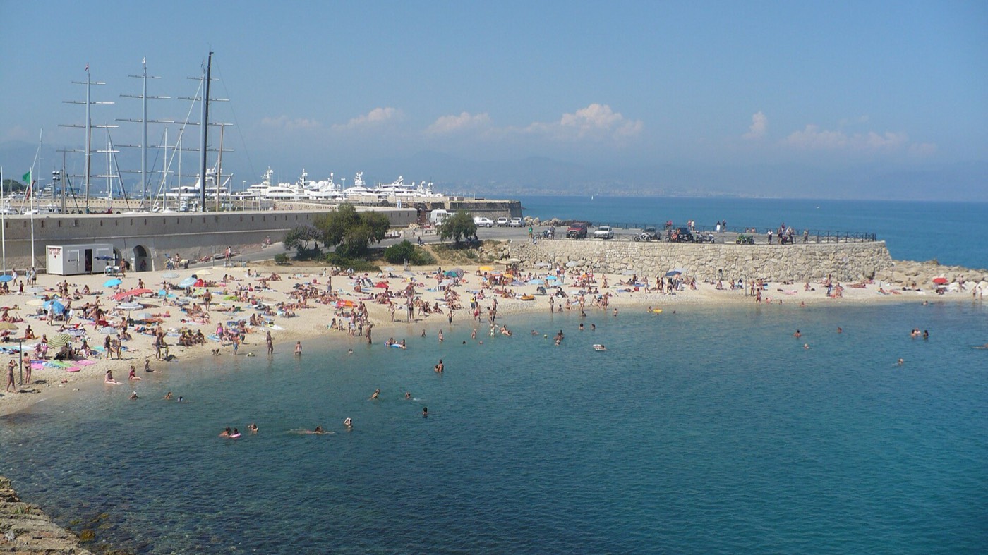 La plage de sable de la Gravette au pied du port d'Antibes, avec les yachts en arrière-plan
