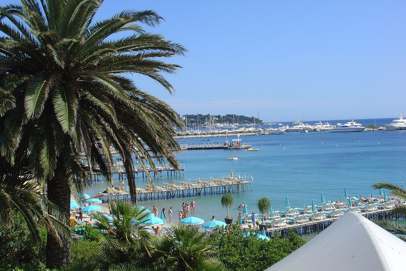 Une plage de Juan-les-Pins avec ses transats bleus et son ponton, sous les palmiers