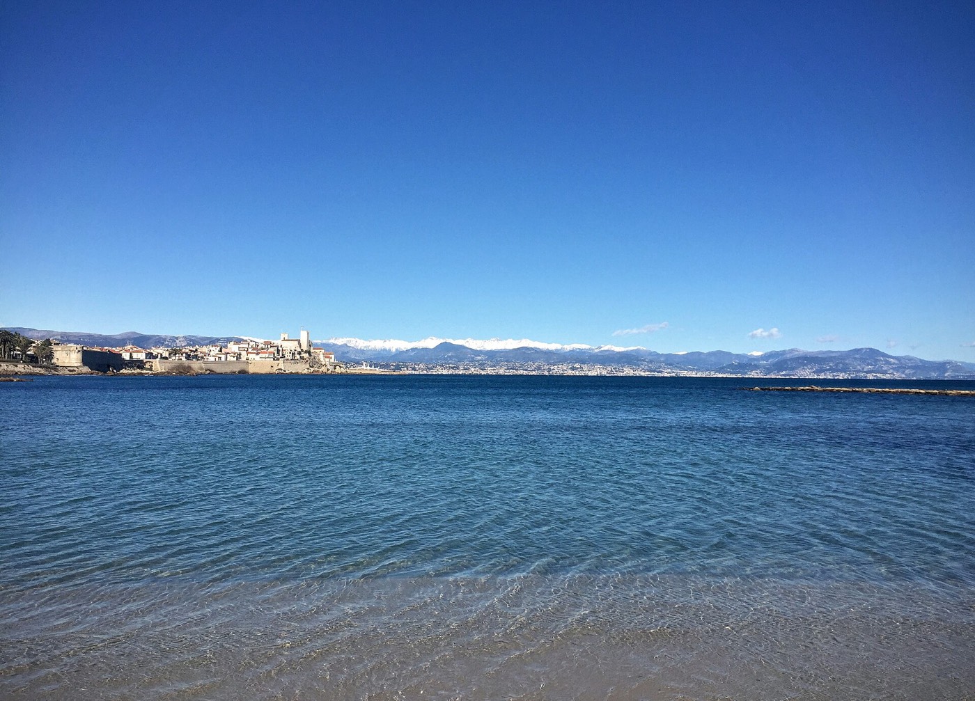 L'eau claire de la plage de la Salis, avec la vieille ville d'Antibes au loin