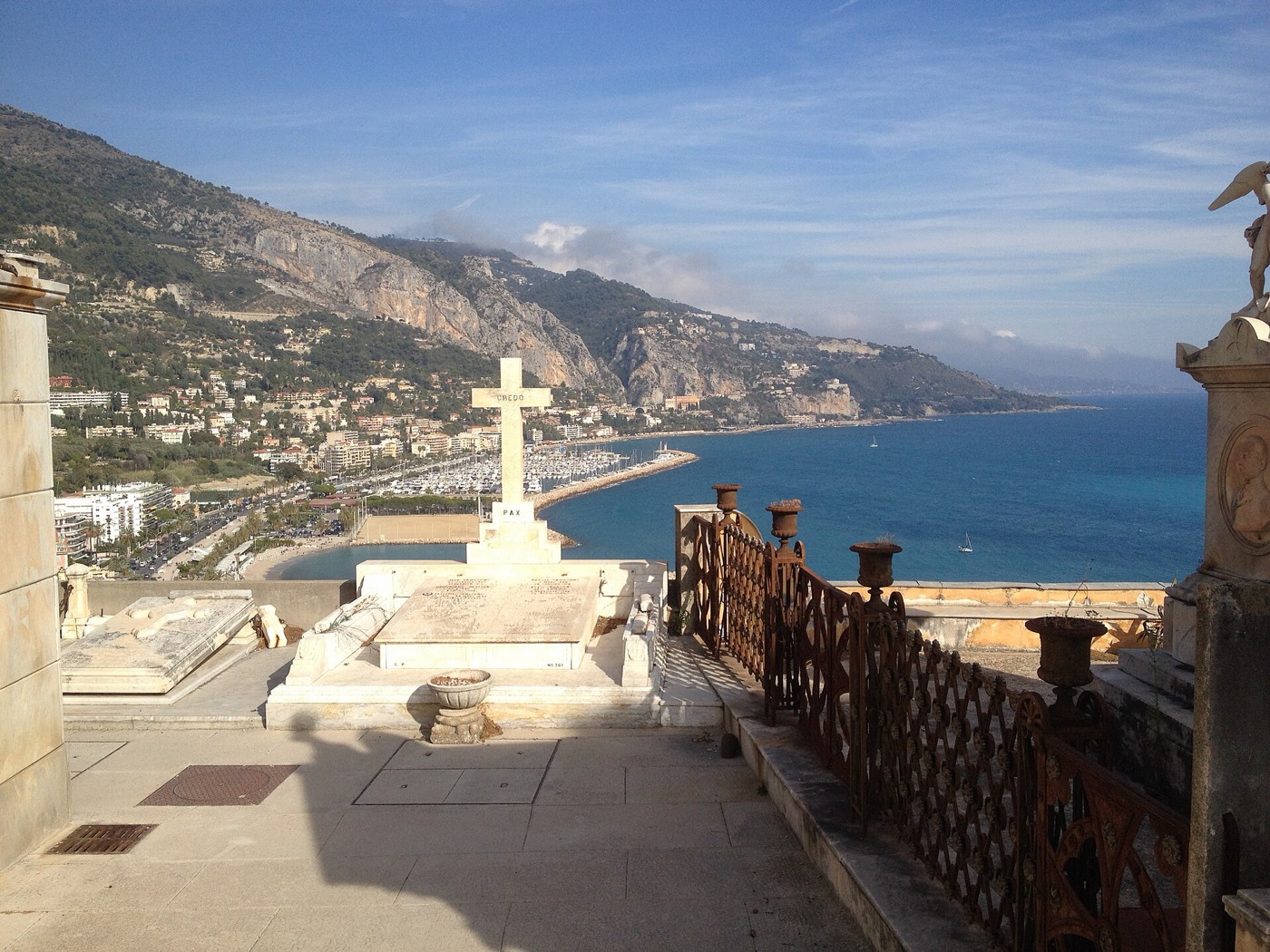 Une tombe blanche du cimetière du Vieux Château, avec la baie de Menton et le port de Garavan en contrebas