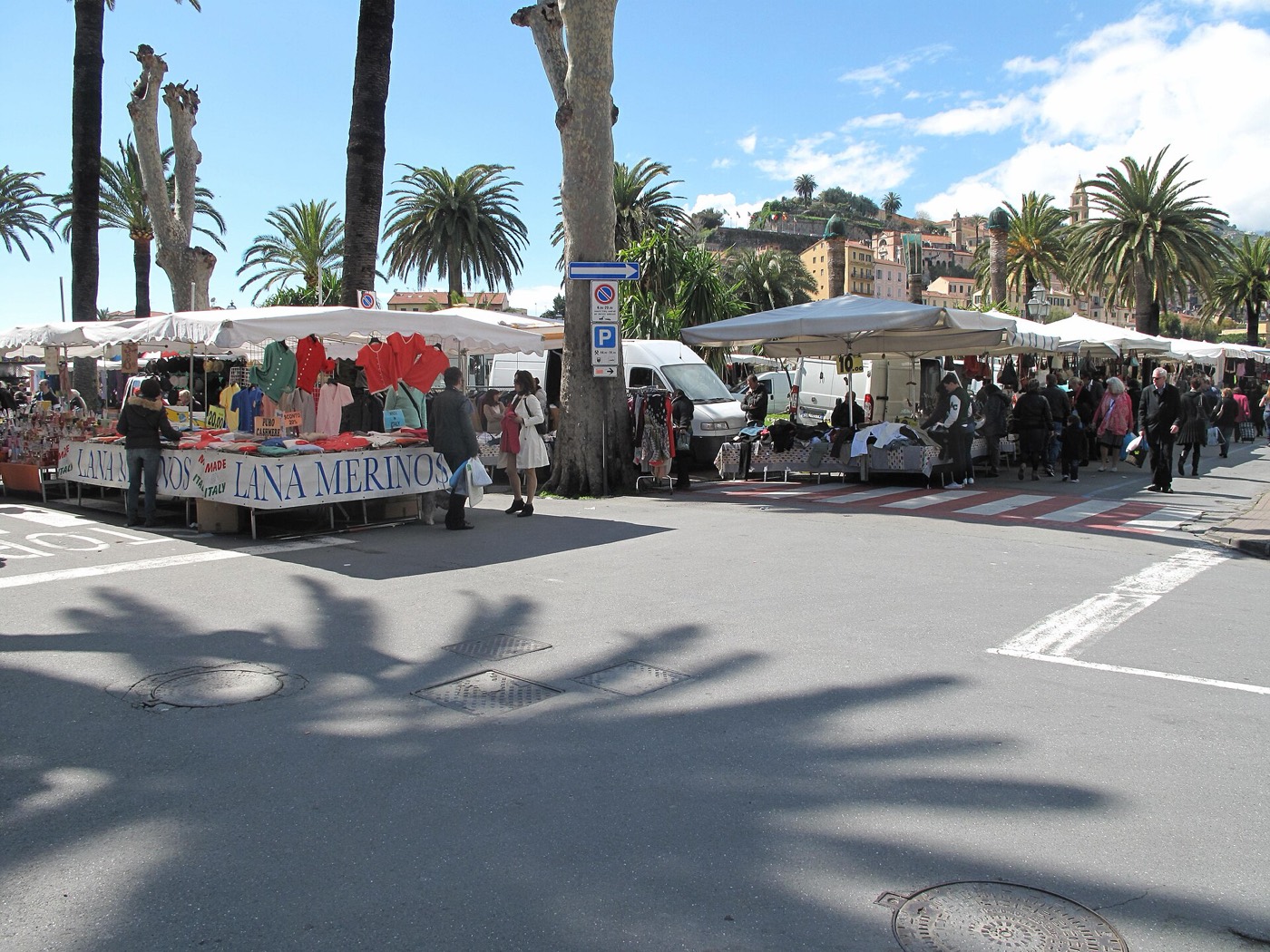 Les étals du marché de Vintimille sous les palmiers, avec la vieille ville en fond