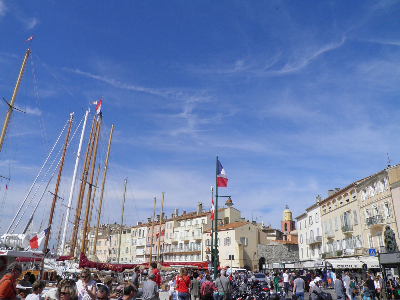 Les mâts des voiliers amarrés au port de Saint-Tropez, devant les façades colorées du quai