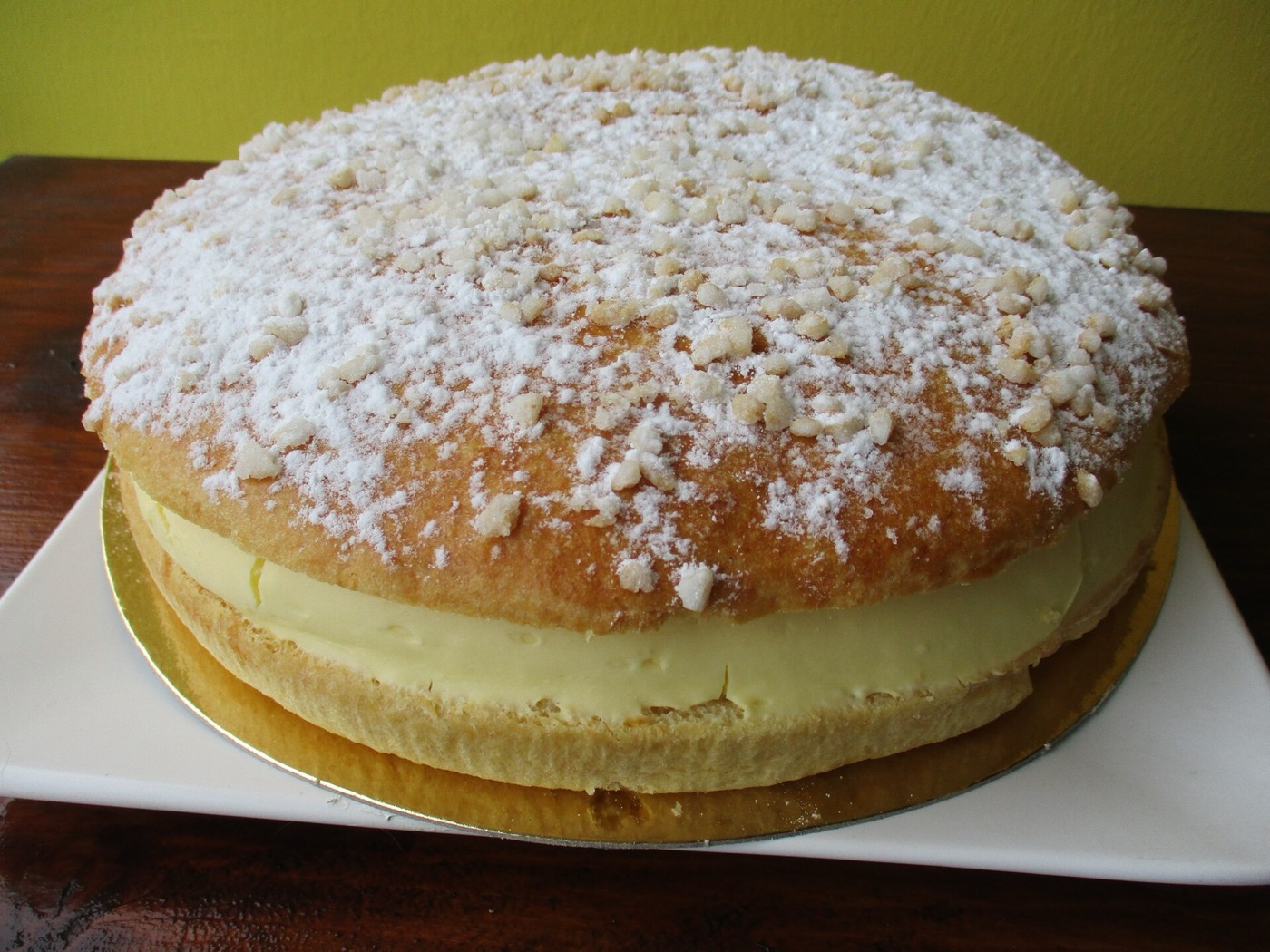 Une tarte tropézienne, brioche garnie de crème et saupoudrée de sucre en grains