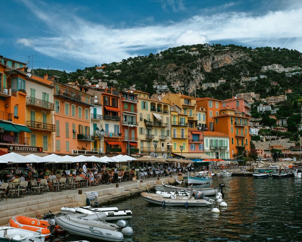 Les terrasses de restaurants et les façades colorées du port de la Santé, avec les barques amarrées au quai